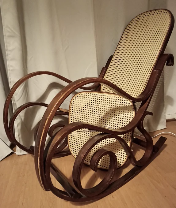 On the photo you can see a swing chair in the style of thonet seen from the side in front of a white curtain. The seat is broken.