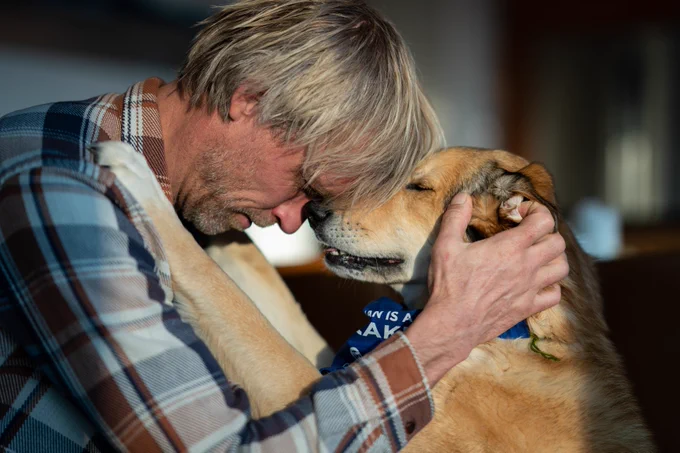 Ben Moon and his dog with their foreheads pressed together. 