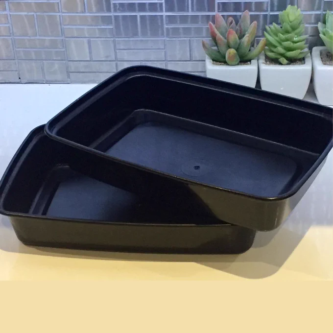 Two empty black plastic containers on a kitchen counter