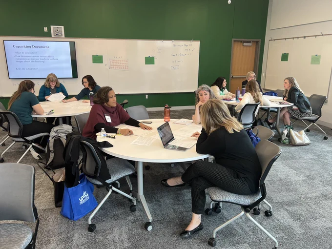 Teachers at round tables talking.