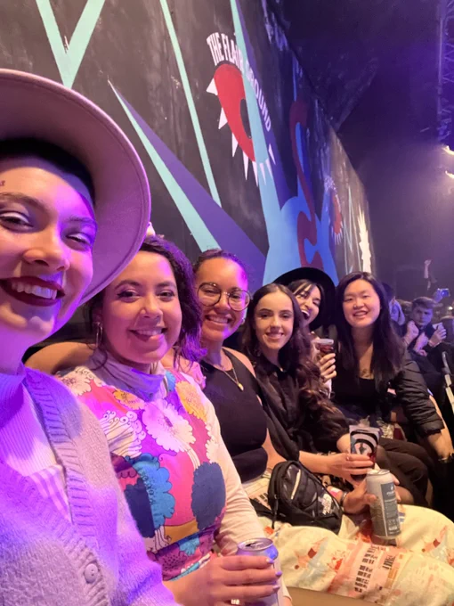 Six members of the Phase cast and crew are seated smiling at the camera excited for the ceremony.