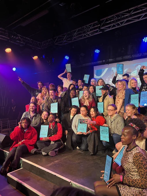 A photo of all the winners of the vault festival awards all very excited with their blue certificates