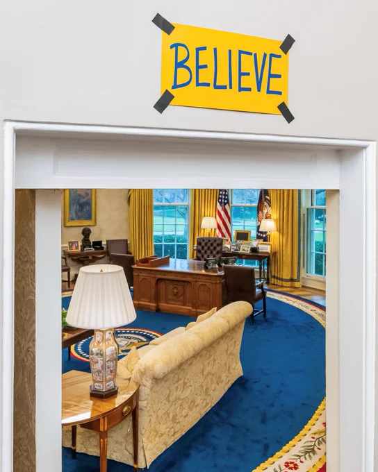 A sign reading "Believe" is taped over a door frame leading into the Oval Office.