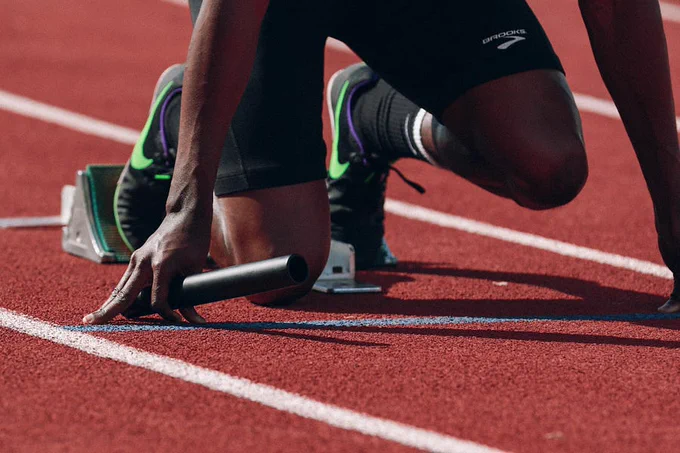 A runner is kneeling on the ground ready to start a race.