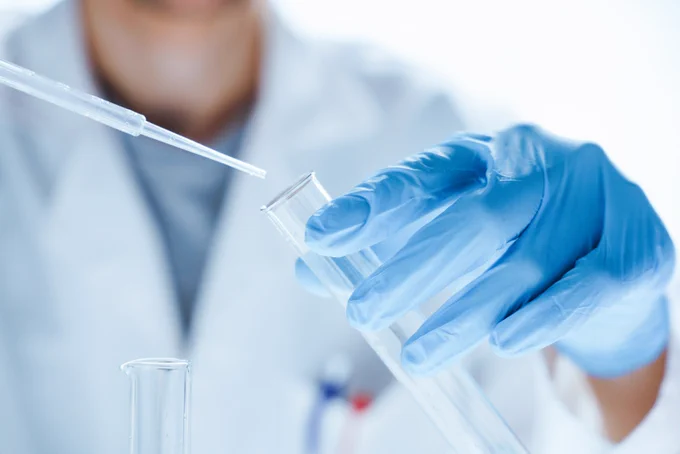 Close-up of a person using a pipette and a test tube  