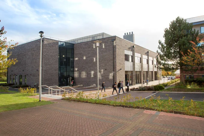 A sunny image of the ISTEC building with students walking outside.
