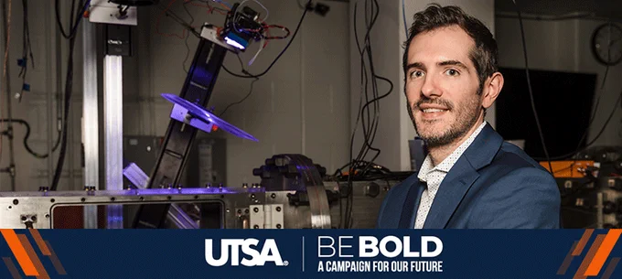 Chris Combs smiles at the camera in his Hypersonics Lab. The banner below the photo reads "UTSA Be Bold, A Campaign for our Future."
