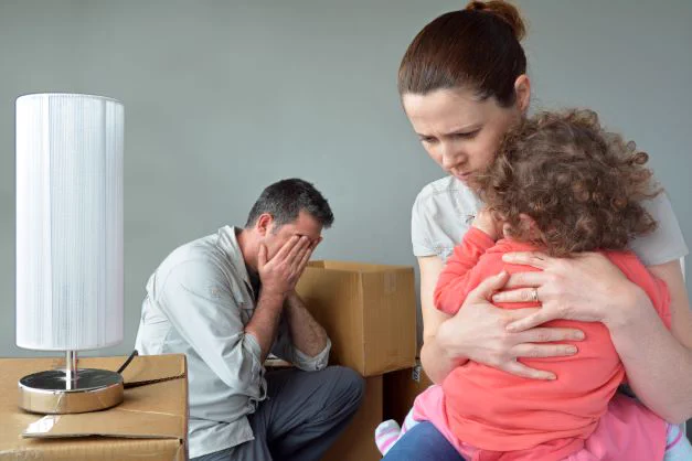 Evicted family packing boxes and looking distraught