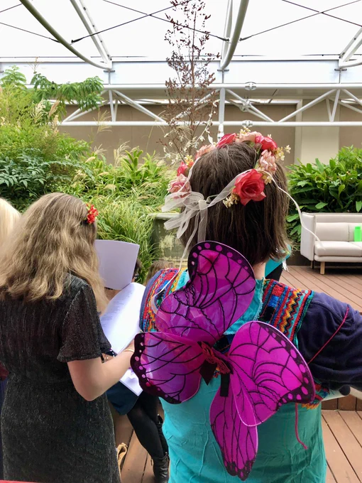A photo of the audience watching the stage. Colourful fairy wings and rose crowns abound.