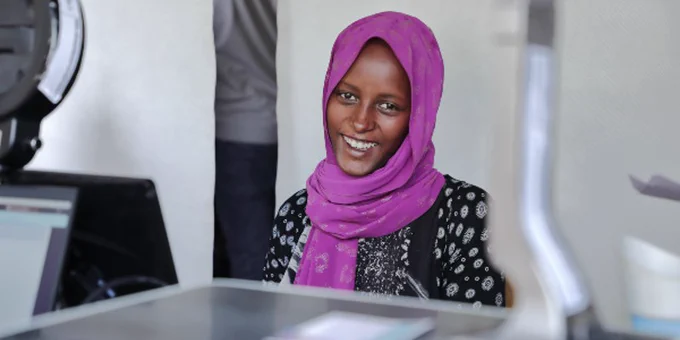 An African woman smiles broadly while getting her biometrics done at the national identity office