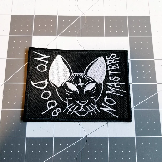White on black embroidered patch with a cat that says no dogs, no masters.