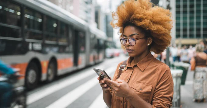 Woman in front of bus looking on her phone