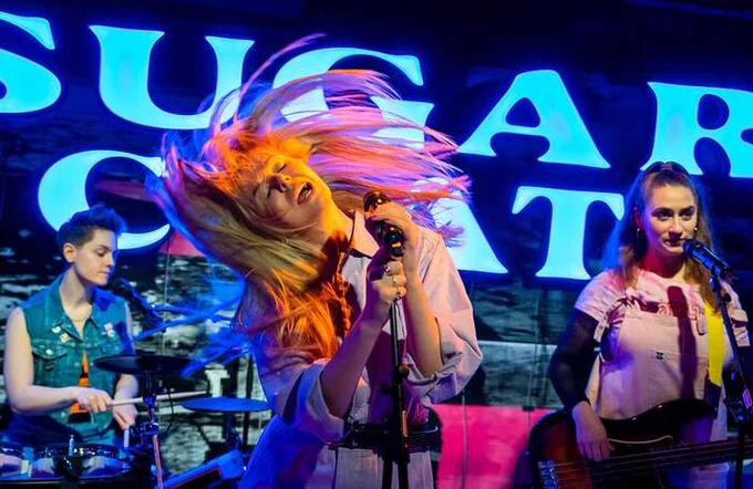 A performer singing into a microphone whilst flipping their hair 