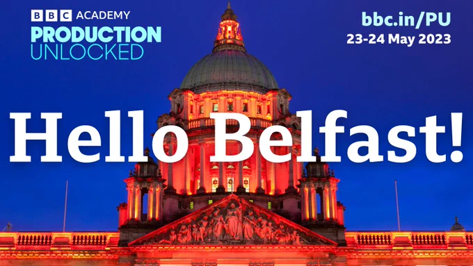 An illuminated Belfast City Hall glows red against a deep blue evening sky.

"Hello Belfast!" is writ large across the photograph.