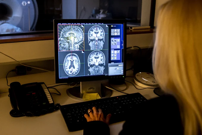 Susan Whitfield-Gabrieli studies four brain scans on a computer. 