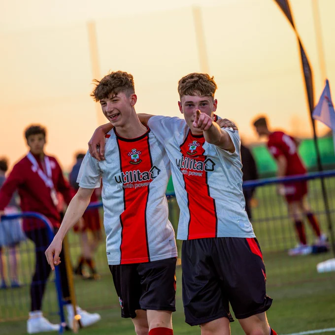 Two of Southampton's Under 16s players wearing the home kit smile and point to the camera in celebration after scoring at the Mina Cup in Dubai