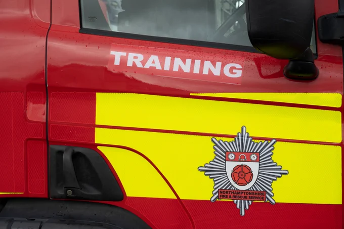 Close up photo of a red Northamptonshire Fire and rescue engine door. There is the word training written in white on the door and a NFRS crest.