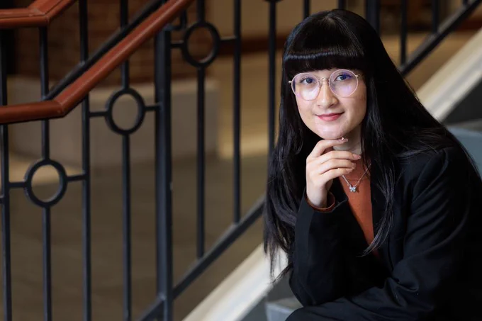 Photo of Sahar Hussaini sitting on the staircase in Cook Hall at the Richard A. Chaifetz School of Business