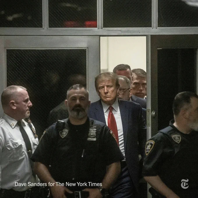 Donald Trump is pictured entering a courtroom in the Manhattan Criminal Courts Building surrounded by law enforcement officers and his own lawyers on Tuesday. Photo credit: Dave Sanders for The New York Times