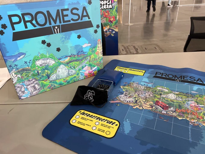 Closeup of promesa board and box (zoomed in view of Puerto Rico in greenfield on a blue background, with illustrations of Arecibo and other iconic locations)