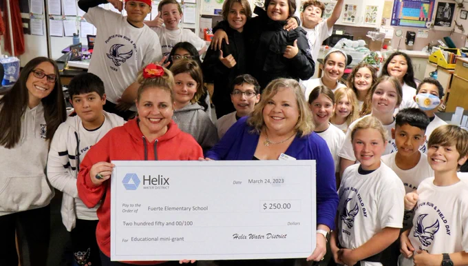Board Member Hedberg holding mini grant check with Fuerte Elementary's 5th grade class.