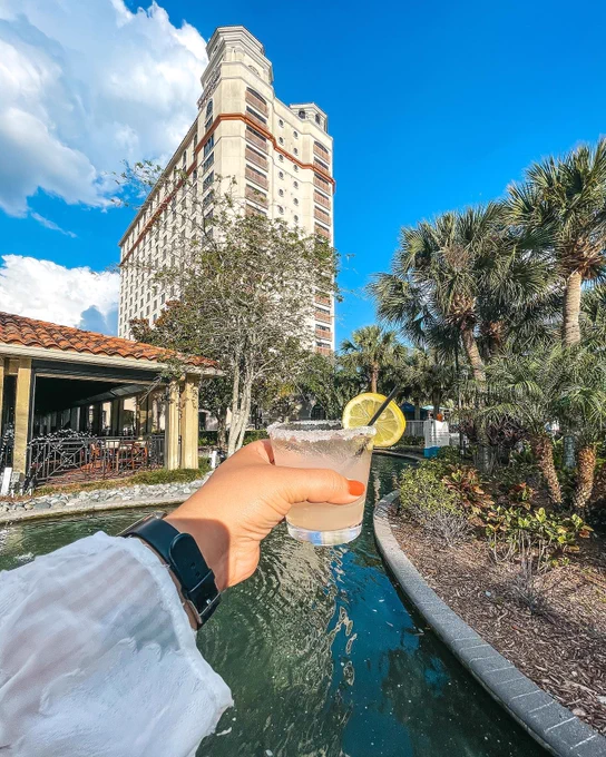 Person holding a drink in front of a pool at the Double Tree Orlando SeaWorld hotel.