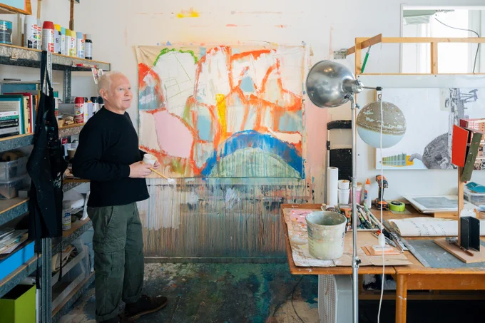 Man stands in studio in front of abstract artwork