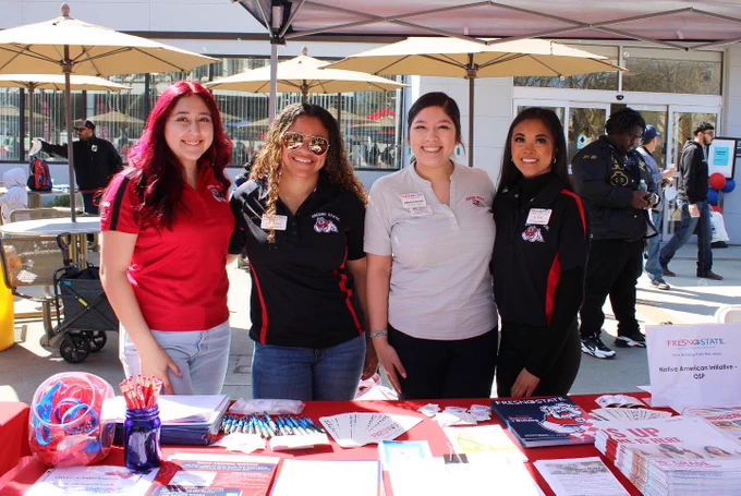 Staff members smiling behind a table with giveaway items for students