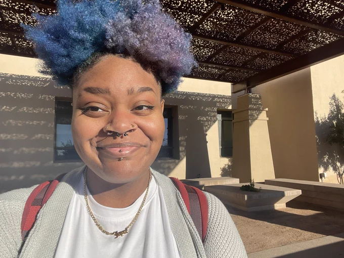 a photo of jayce, person with blue and purple curly hair, at utep with a grey cardigan and white shirt