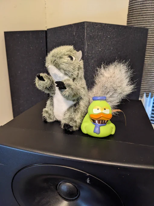 A squirrel finger puppet and a rubber duck sit on top of a speaker