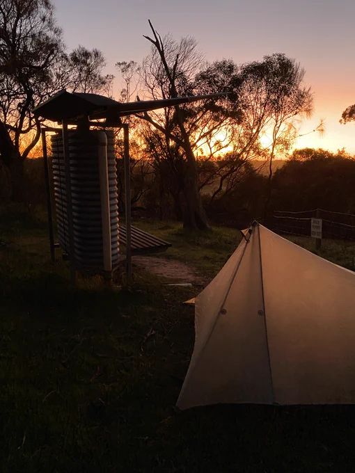 Tent beside a tank at sunrise, with the pink and orange glow lighting up the material