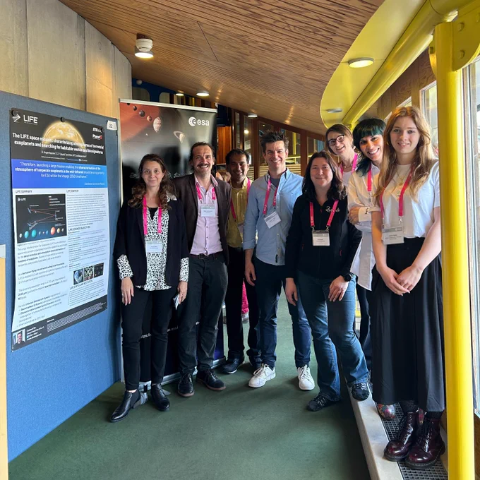 A group of smiling people next to a scientific poster at a conference 