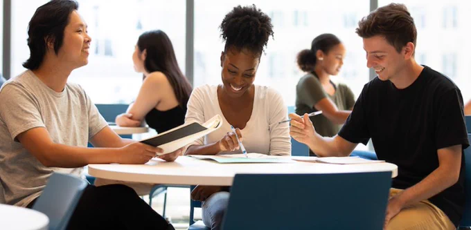 Three students sitting at table and studying.