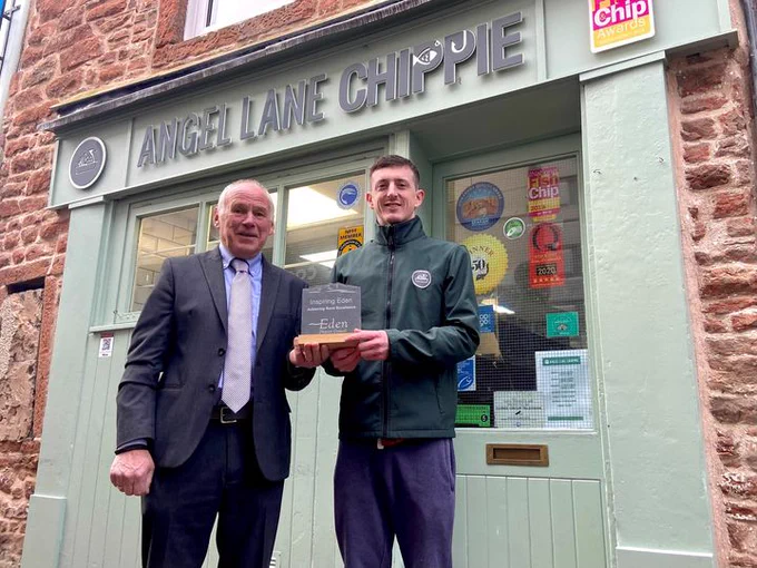 Image: Dan Harding receiving an Inspiring Eden Award by Douglas Banks, Chairman of Eden District Council. Standing outside Angel Lane Chippie, Penrith.