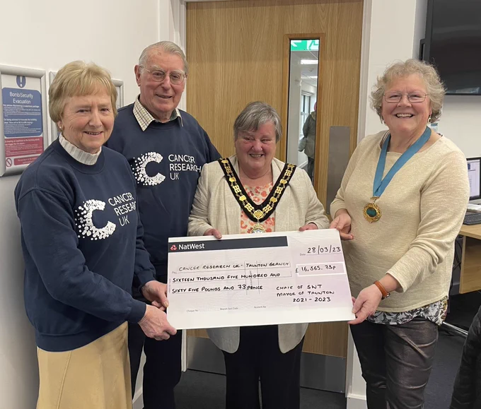 Chair and Mayor stood in the Council Chamber with two charity representatives and a giant presentation cheque