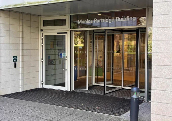 Main entrance to the Monica Partridge building taken from outside. Automatic and accessible door to the left and rotating doors in the centre.