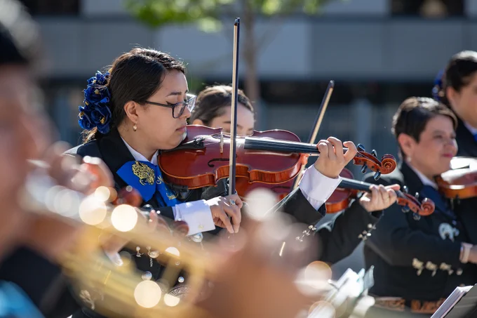 A student mariachi band plays with focus on a young woman playing violin.