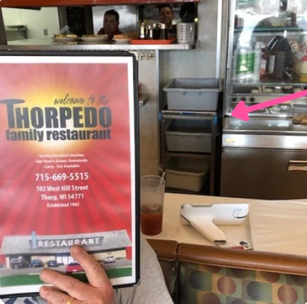 Image of a Lakeside utility cart in the background at a restaurant with someone holding up a menu. 