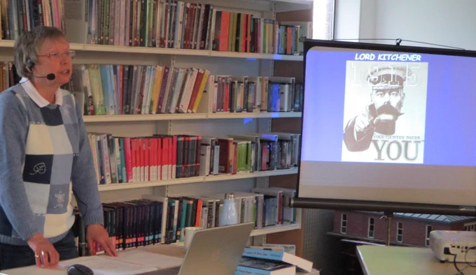 speaker delivering talk with projector screen showing image of lord kitchener