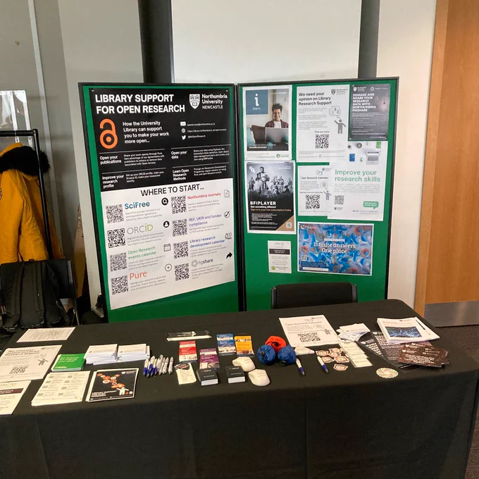 Photo of the open research stall. There are a number of flyers and pens / pencils on the table. 