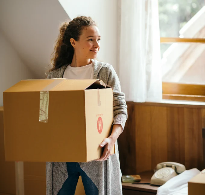 Student holding a box in a bedroom