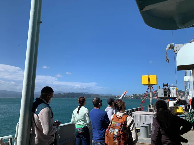People on the deck of the research vessel pointing and looking towards a part of the ship.