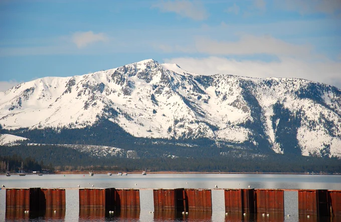 Photo of snow covered Sierras in California with a lake in the foreground