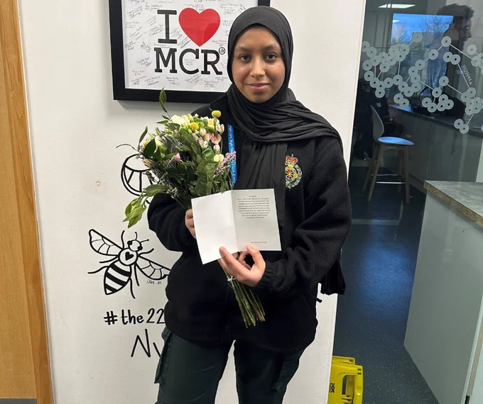 Emergency Medical Advisor Maryam holding flowers and a thank you card.