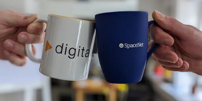 Die Hände von zwei Personen sind zu sehen, die mit Kaffeebechern anstoßen. Auf dem rechten, blauen Becher ist das Logo der SpaceNet AG zu sehen, auf dem linken, weißen Becher das Logo von Digitalcourage. 