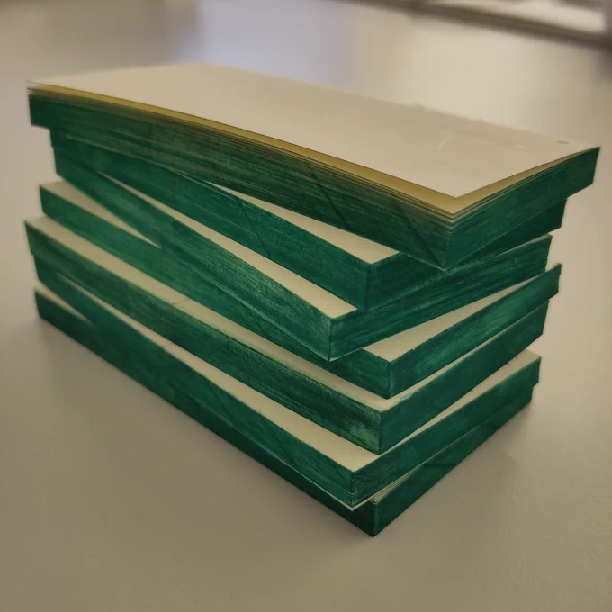 A stack of small books with bright green book edges is lying on a table.