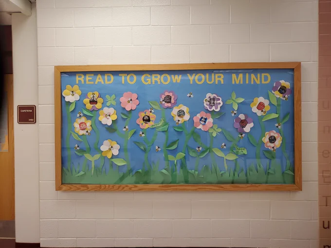 Bulletin board with flowers, grass, butterflies, caterpillars reads, "Read to grow your mind"