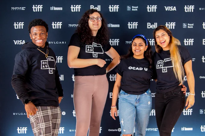 Photo on black with white logos TIFF backdrop of OCAD U LiVE content creators smiling at the camera. From left to right: Christian Markland, Wrynn Geswin,  Mina Vekaria and Amanda Campos.