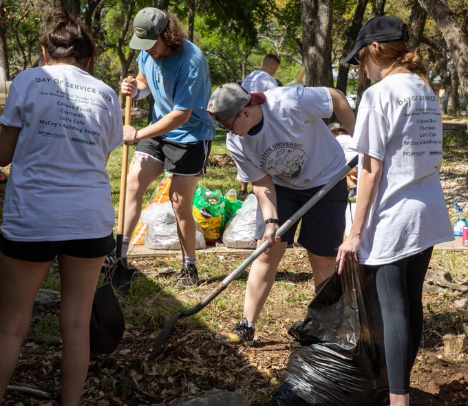 TXST students racking and shoveling a flower bed during Bobcat Build
