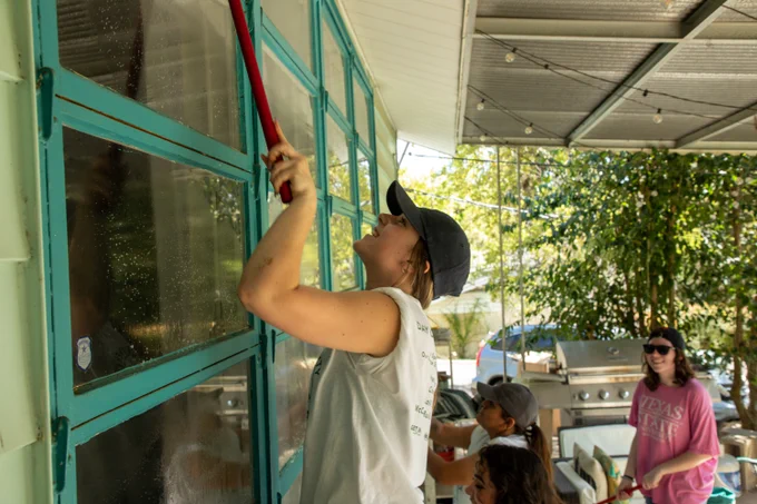 TXST student cleaning windows during Bobcat Build, a community service day event